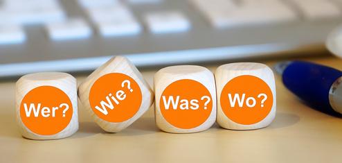 Holzwürfel mit orange-farbendem Kreis und W-Fragen